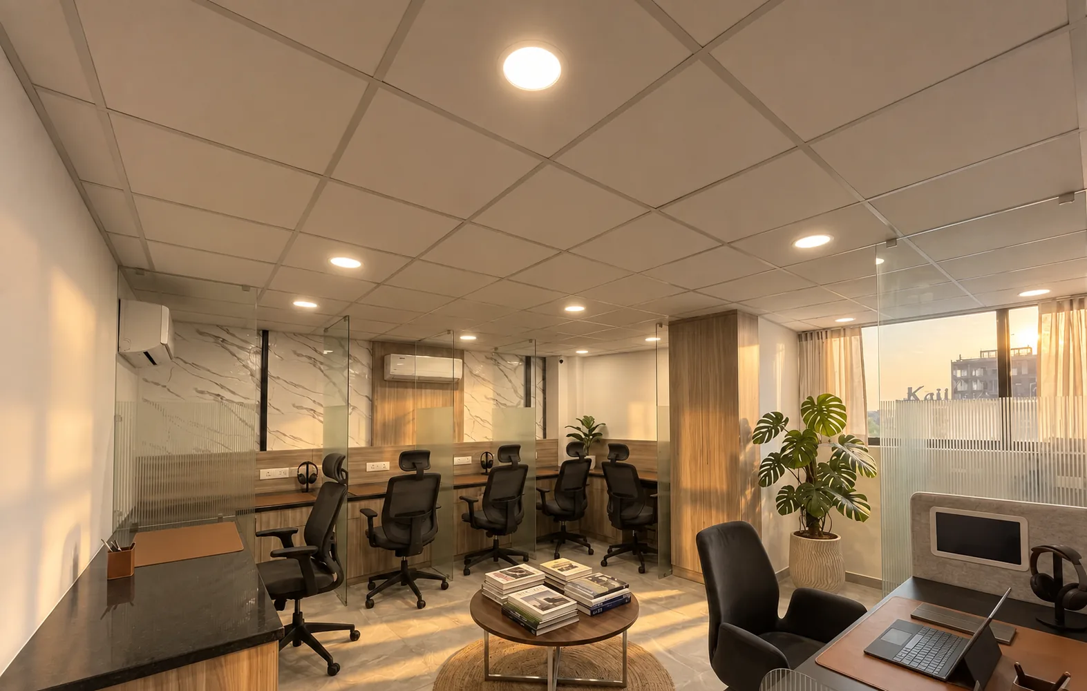 The work cube: glass-divided desks with black mesh chairs, a round table of books and a window